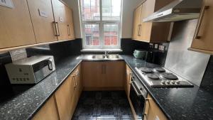a small kitchen with a stove and a microwave at Sangha Hall - Private Ensuite Rooms with Shared Kitchen in Leicester
