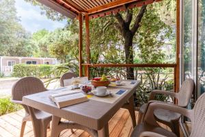 a table and chairs on a patio with a tree at Club del Sole Jesolo Family Resort in Lido di Jesolo