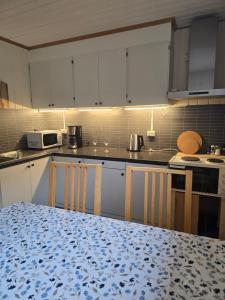 a kitchen with white cabinets and a table with chairs at Hamrebakken overnatting in Kvinesdal +24 photos