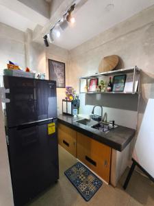 a kitchen with a black refrigerator and a sink at Staycation by ALCD in San Mateo