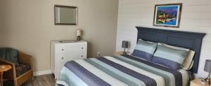 a bedroom with a bed and a chair and a mirror at Crimson Sky Cottage in Twillingate