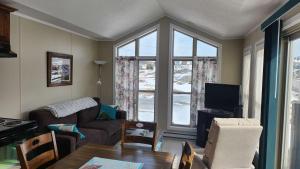 a living room with a couch and a table and a window at Crimson Sky Cottage in Twillingate