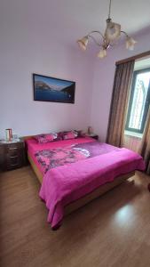 a bedroom with a large bed with a purple blanket at Apartment Capt Seferovic 2 in Donji Morinj