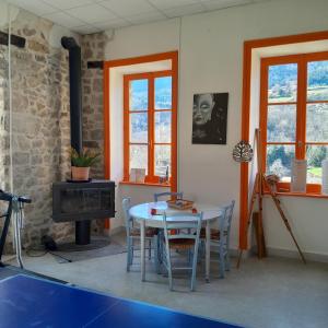 a dining room with a table and a stove at gite que canta in Saint-Julien-Vocance