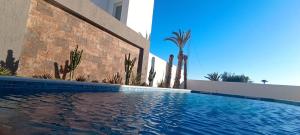 a swimming pool in front of a building with cactus at Villa AM in Awlād ‘Umar