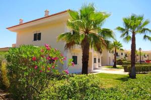 a house with palm trees and flowers in a yard at Formosa Villas in Quinta do Lago