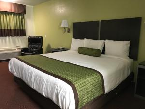 a hotel room with a large bed and a chair at Southern Inn Minden in Minden