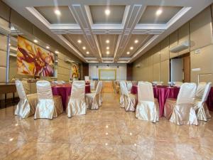 a conference room with a long table and white chairs at Olympic Hotel Jakarta in Jakarta