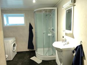 a bathroom with a shower and a sink and a washing machine at Hamrebakken overnatting in Kvinesdal