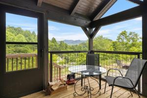 a screened in porch with a table and chairs at Smoky Mountain Mist, Tiny House, Custom Log Cabin in Bryson City
