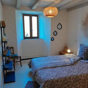 a blue bedroom with a bed and a window at gite que canta in Saint-Julien-Vocance