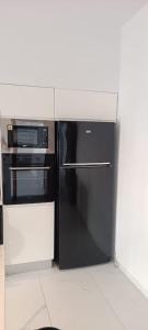 a kitchen with a black refrigerator and a microwave at Villa AM in Awlād ‘Umar