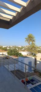 a balcony with a view of a beach and a palm tree at Villa AM in Awlād ‘Umar