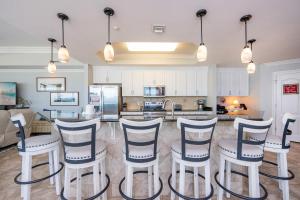 a kitchen with white cabinets and bar stools at The Oasis 411 formerly Phoenix West II 411 in Orange Beach