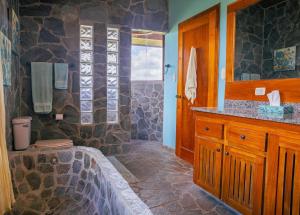 a bathroom with a stone shower with a tub and a sink at Villa Siempre Aventura in Nuevo Arenal +32 photos