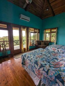 a bedroom with a bed and a couch and windows at Villa Siempre Aventura in Nuevo Arenal