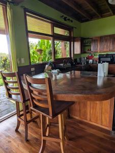 a kitchen with a large wooden island with two chairs at Villa Siempre Aventura in Nuevo Arenal