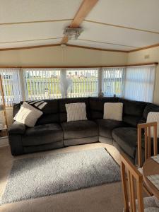 a living room with a black couch in front of a window at Browns caravan rentals, ingoldmells 4 berth caravan silver beach in Ingoldmells
