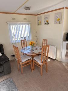 a dining room table with two chairs and a table and a window at Browns caravan rentals, ingoldmells 4 berth caravan silver beach in Ingoldmells