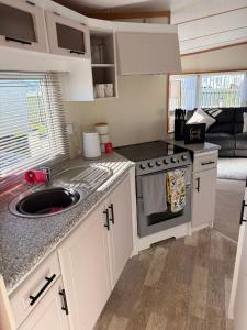 a kitchen with a sink and a stove at Browns caravan rentals, ingoldmells 4 berth caravan silver beach in Ingoldmells