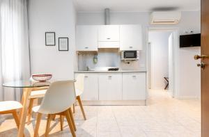 a kitchen with white cabinets and a table and chairs at HB Appartamenti in centro Bergamo in Bergamo