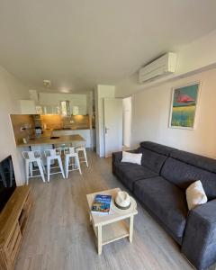 a living room with a couch and a table at BADINE BEACH 5 personnes vue jardin avec climatisation in Hyères