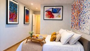 a living room with a white couch and some paintings at Alta Luminara Boutique Residence Sea View Terraces Marbella Hills in Benahavís +33 photos