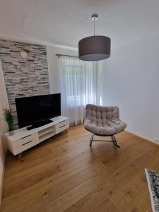 a living room with a chair and a flat screen tv at Ferienwohnung Claudia Alt-Ossiach in Altossiach