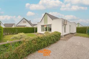 a white house with a hedge in front of it at Nieuwendamme 69 with pool and parking in Nieuwpoort