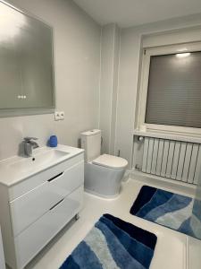 ein Badezimmer mit Waschbecken, Toilette und blauen Teppichen in der Unterkunft Traumwelt in Flemlingen