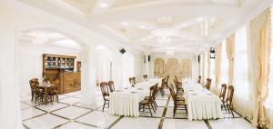 una grande sala da pranzo con tavoli e sedie bianchi di Hotel Korona a Kolybayevka