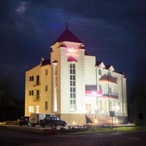 a large building with a sign on it at night at Hotel Korona in Kolybayevka