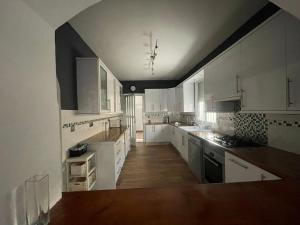 a large kitchen with white cabinets and wooden floors at Villa Sparrow, Arboleas in El Arroyo Aceituno