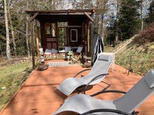 a wooden deck with chairs and a cabin at un ptit chalet in Les Brenets