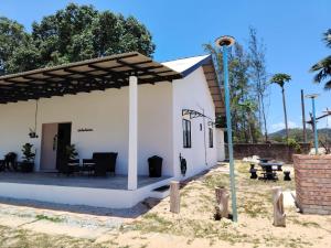 a white house with a patio and a table at Bayu Beach House in Cherating