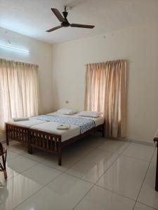 a bedroom with two beds and a ceiling fan at Basuri Beach Resort in Varkala