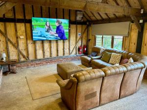 a living room with a couch and a flat screen tv at Locks Lane Cottage in Geldeston