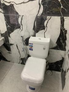 a white toilet in a bathroom with marble walls at Sansa HomeStay in Bandarawela +4 photos