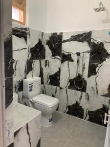 a bathroom with a toilet and a black and white marble wall at Sansa HomeStay in Bandarawela