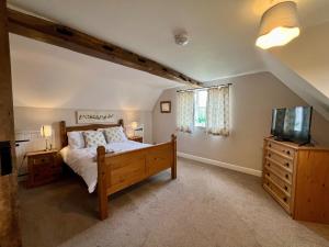 a bedroom with a bed and a flat screen tv at Locks Lane Cottage in Geldeston +42 photos