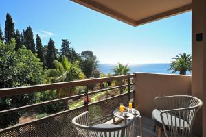 a balcony with chairs and a table with a view of the ocean at La Réserve Esterel in Saint-Raphaël