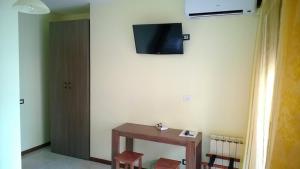 ein Zimmer mit einem Tisch und einem Fernseher an der Wand in der Unterkunft Villa Dante BB via Catania162 in Messina