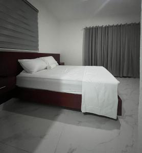a bedroom with a bed with white sheets and a window at RUKA Hotel in Punta Cana