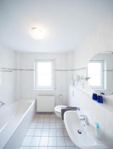 a white bathroom with a tub and a sink at Ferienwohnung am Moselufer in Cochem +3 photos