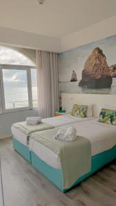 two beds in a bedroom with a large window at Golden Beach Guest House & Rooftop Bar in Faro