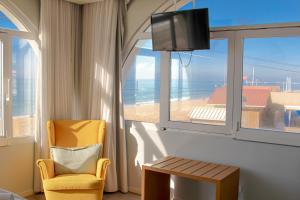 a room with a window with a chair and a television at Golden Beach Guest House & Rooftop Bar in Faro