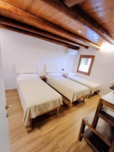 two beds in a room with wooden floors at Al Colle Rooms in Montebello Vicentino +15 photos