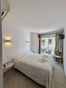 a white bedroom with a large bed and a balcony at Pensió Anna in Tossa de Mar
