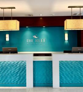 a reception desk with two laptops on a blue wall at The Reef Beach Resort, East End, Grand Cayman in Sand Bluff +79 photos