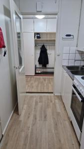 a kitchen with white cabinets and wood floors and a door at Economy stay - Self Check-in in Vaasa